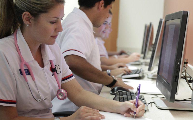 a nursing student taking notes while at a computer